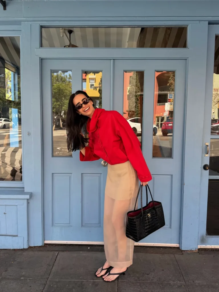 A Red Cropped Jacket With Sheer Beige Trousers