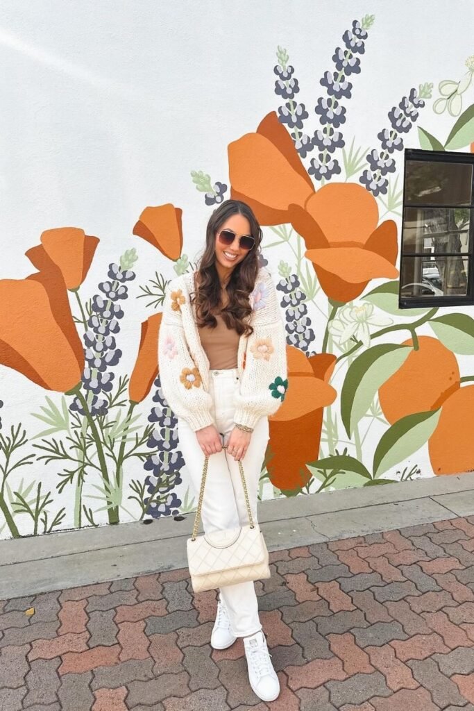 A Hand Knit Floral Cardigan Over Cream Denim